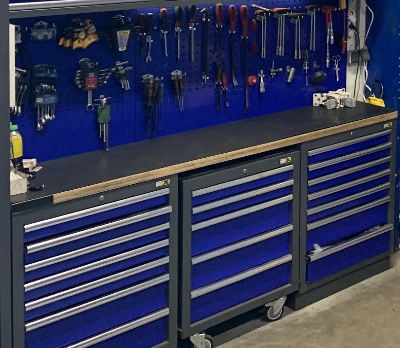 Blauwe gereedschapswand met ladekasten en werkbank