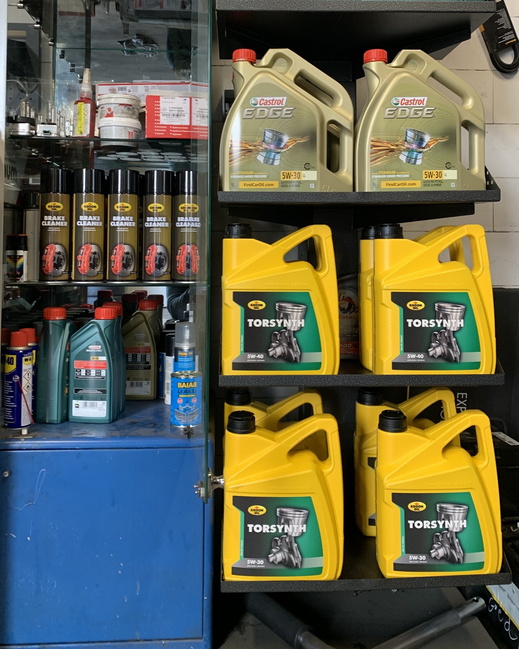 Stelling met motorolie en onderhoudsmiddelen van Castrol en Kroon-Oil in de werkplaats
