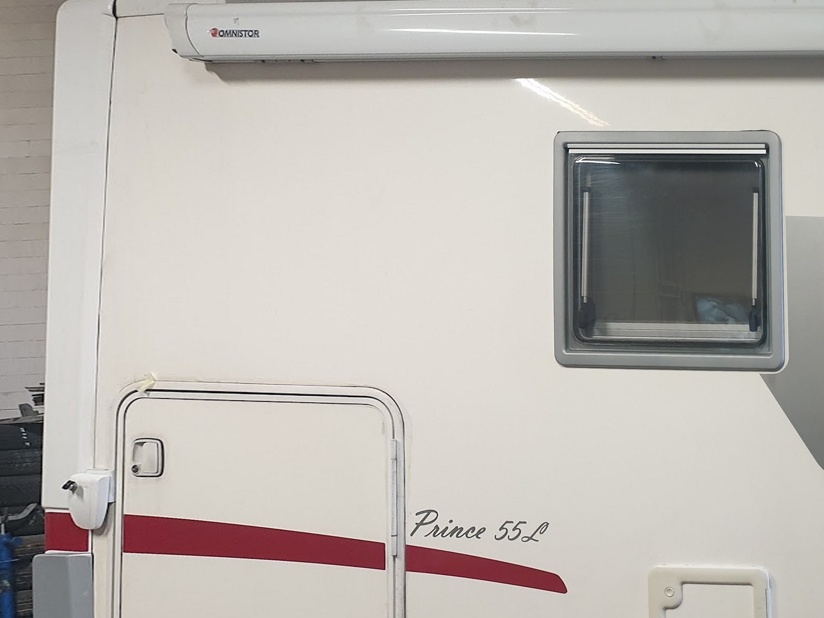 Een camper in de werkplaats van Autobedrijf Hoogeind, naast de bandenstapel